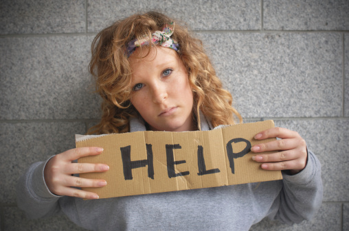Young, teenage, girl, outdoors, holding a sign for help, looking at camera.