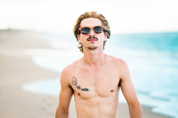 istock Handsome cool young gen z guy in swimsuit on the beach 1607804323