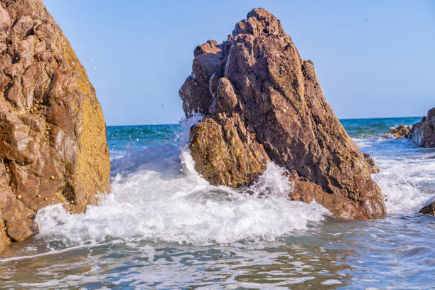 Waves crashing around a rock on Kennack Sands Beach, Cornwall, UK. Captured in July 2023.