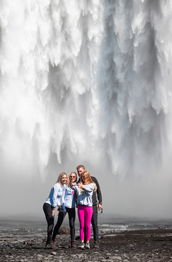 Skogafoos waterfall, iceland - July 20 2022: A group of friends or family taking a photo in front of the waterfall