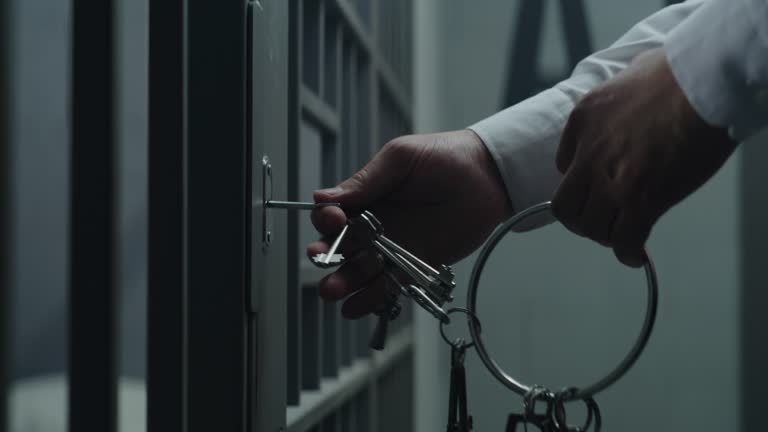 Close up of jailer opening and locking prison cell with keys