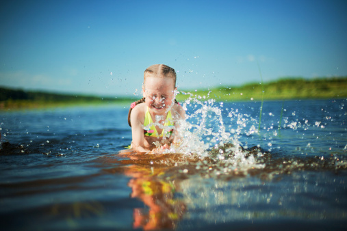Little girl splashing in a river. Focus on a drops.