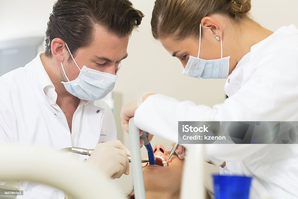 Patient with Dentist - dental treatment Female patient with dentist and assistant in a dental treatment, wearing masks and gloves Active Seniors Stock Photo