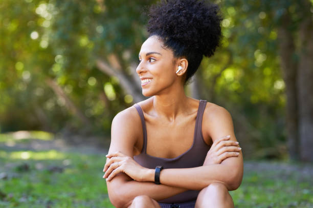 Beautiful young woman with afro ponytail sitting in park after trail run stock photo