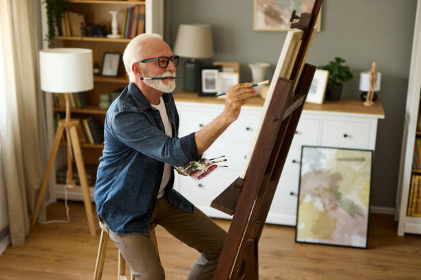istock Elderly man painting on a canvas at home 1607858457