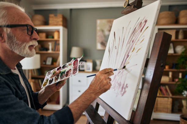 istock Elderly man painting on a canvas at home 1607860582