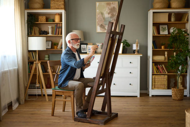istock Elderly man painting on a canvas at home 1607861679