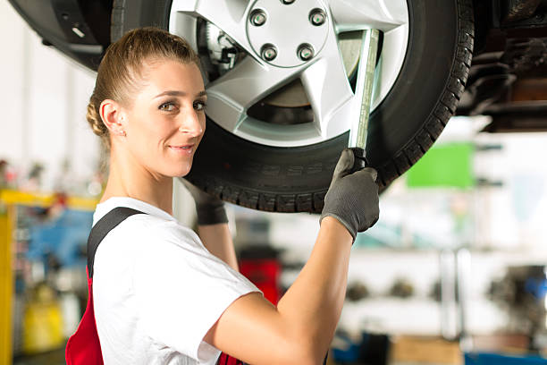 istock Female car mechanic working on jacked auto 160786176