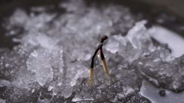 Two Burning Matches are Connected in a Flame of Fire on Wet Snow. Close up