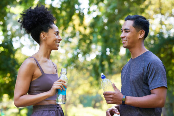 istock Fitness team cools down after exercise in park, beautiful couple drinking water 1607871239