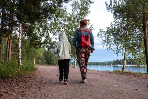 A family of Caucasians on an evening walk walks by the lake. A girl of 8 years old and a young woman spend time together on vacation admiring the beauty of nature. A family of Caucasians on an evening walk walks by the lake. A girl of 8 years old and a young woman spend time together on vacation admiring the beauty of nature. saimaa stock pictures, royalty-free photos & images