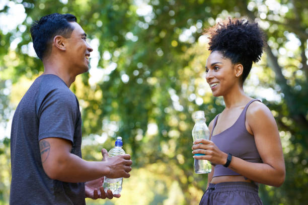 istock Fitness team cools down after exercise in park, beautiful couple drinking water 1607880619