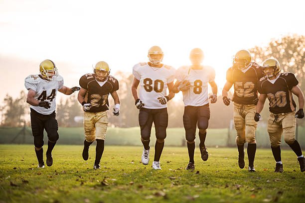 College Football players. American football players running on the playing field.    wide receiver athlete stock pictures, royalty-free photos & images