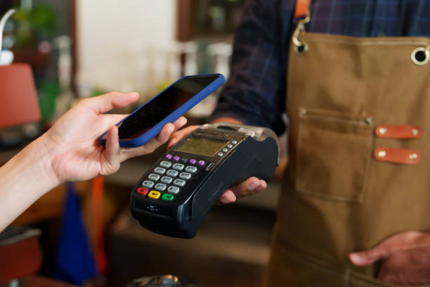 istock Close-up customer hand is using smartphone to scan QR code from credit card reader to pay for coffee and bakery. Minimize contact and don't use cash to pay. In a cafe while traveling 1607909394
