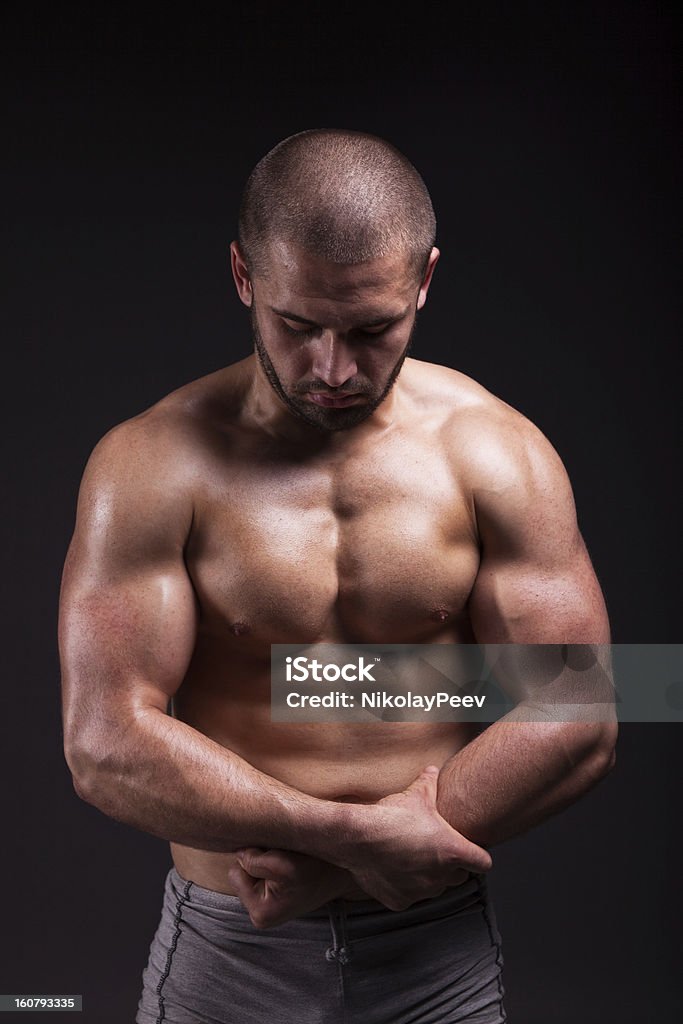 Muscular man showing músculos aislado sobre fondo negro - Foto de stock de Adulto libre de derechos