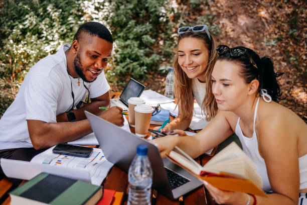 Multiracial group of people studying in park while sitting on park bench