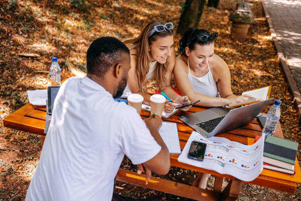 istock Group of students learning outside in public park 1607942381