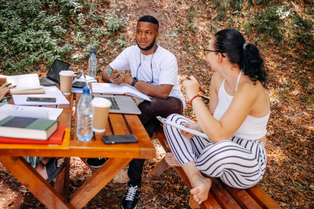 istock Group of students learning outside in public park 1607943547
