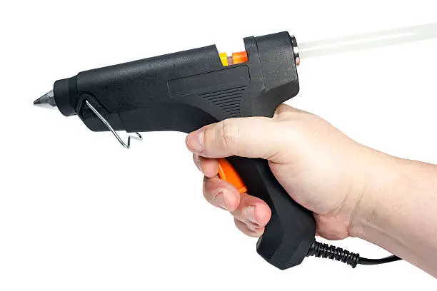 Electric hot glue gun in hand isolated on a white background.