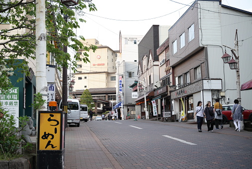 Noboribetsuonsencho, Japan - June 6, 2023: Visitors walk along Gokuraku Street in the popular retail district by Jigokudani, Hell Valley. Spring afternoon in Iburi Subprefecture of Hokkaido Prefecture.