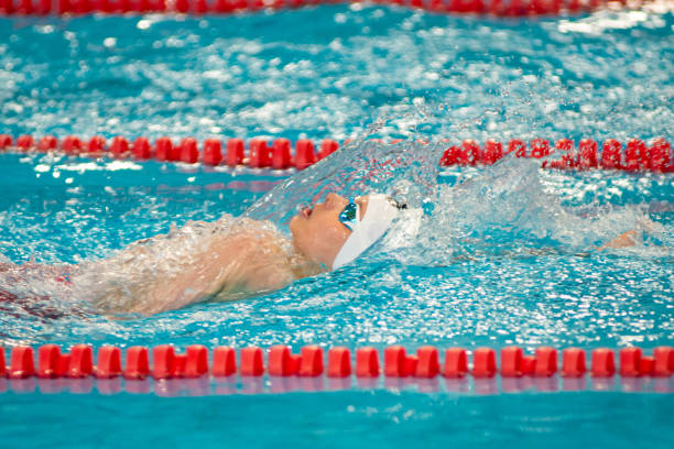 Swimmer boy swims backstroke swimming style in the pool