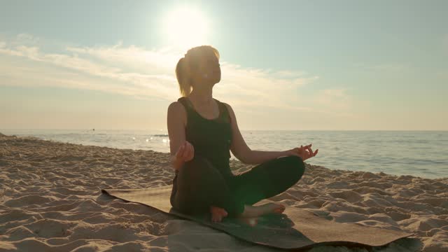 Woman sitting in meditation pose on sea beach lotus position medicine yoga asana balance kundalini energy every day routine practice