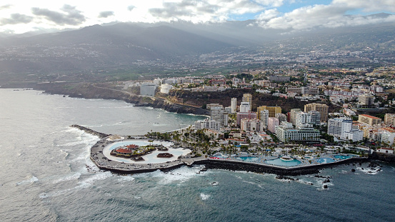 Captured from the skies above, this breathtaking aerial shot showcases the vibrant cityscape of Puerto de la Cruz. The drone's perspective reveals the intricate layout of the city, nestled beautifully alongside the serene bay.