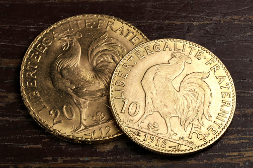 French 10 and 20 Francs gold coins (reverse with rooster) on rustic wooden background