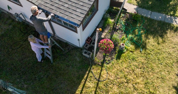 istock Senior man cleans roof gutter, his partner holds ladder for him 1608068251