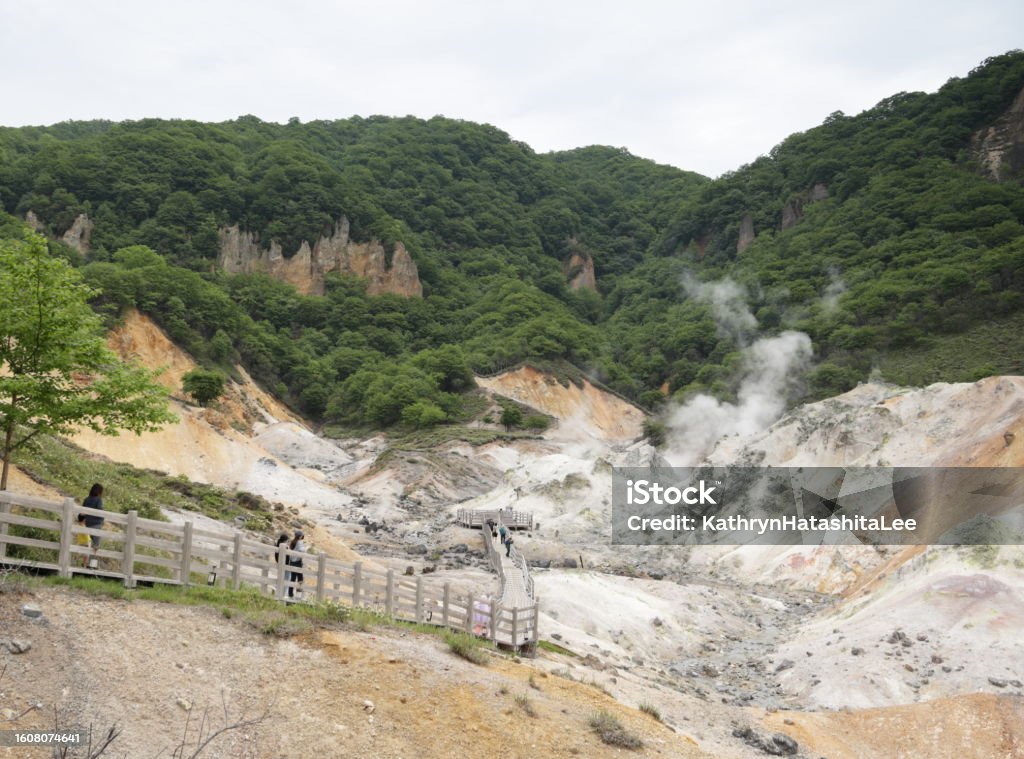 Volcanic Crater in Shikotsu-Toya National Park, Japan Resort visitors go along an elevated boardwalk to the Observation Deck in Jigokudani, Hell Valley. Gases escape from the many fumaroles on the volcanic crater. Spring afternoon in Iburi Subprefecture. Hokkaido Stock Photo