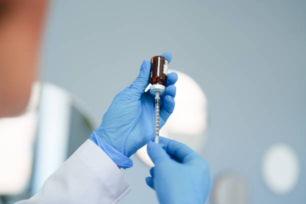 Nurse with Blue Gloves Filling Syringe