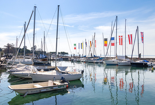 Sailing boats and flags of european countries at harbour of Bardolino