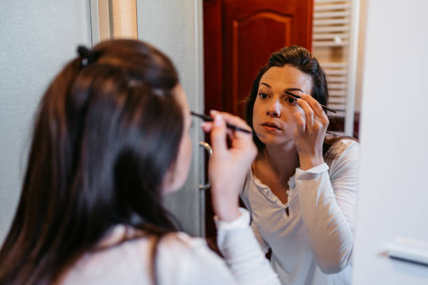 istock Young Woman Applying Makeup In The Bathroom 1608084068