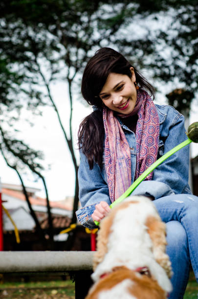 istock middle aged woman playing with dogs in park 1608106745