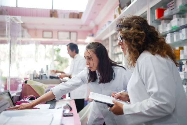 istock Pharmacist and assistant working behind the counter at the computer 1608121945