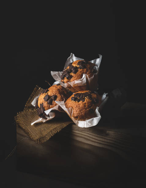 cupcakes with chocolate chips, on a wooden drawer, illuminated from the side, dark mood style