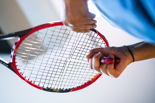 Close-up shot of hands stringing the racket on stringer