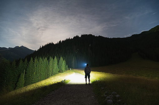 Night scene, the silhouette of a man with a headlamp goes hiking in the Tatra Mountains in summer time. High quality photo