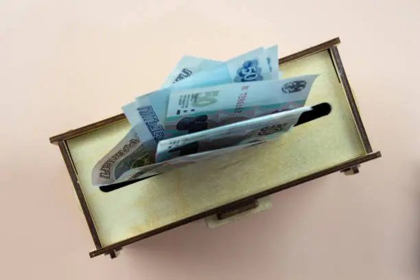 A wooden coin bank with 50-ruble bills in the slot