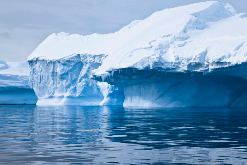 Antarctica Turquoise Blue Glacier Iceberg drifting on the Antarctic Ocean under overcast cloudscape. Antarctica Ocean - Antarctica Sound, Antarctica.