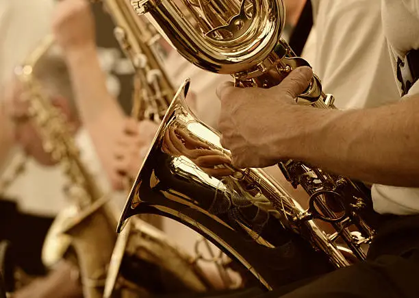 A close view of a polished saxophone and the player's arm. Depth of field with focal point on foreground