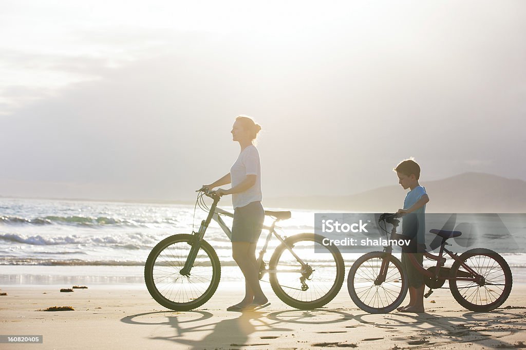 Mother and son with bikes Mother and son with bikes on a beach at sunset Cycling Stock Photo