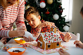 Mother icing gingerbread house for the Christmas holiday
