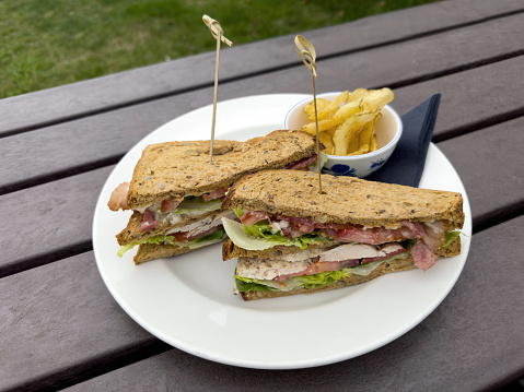 Club sandwich made with chicken, ham tomato and salad with potato crisps