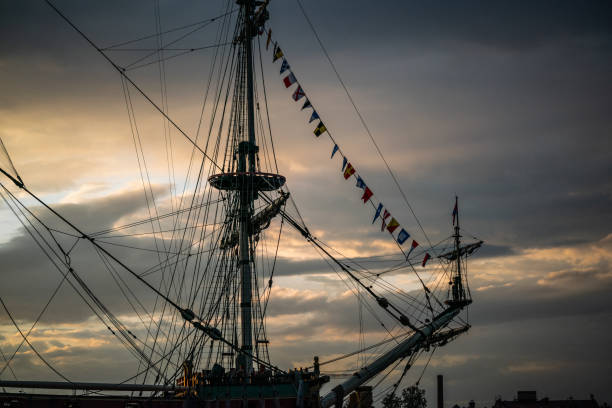Masts of old ship against sunset clouds