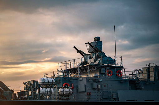 Military carrier turrets and weapons on warship at sunset close-up