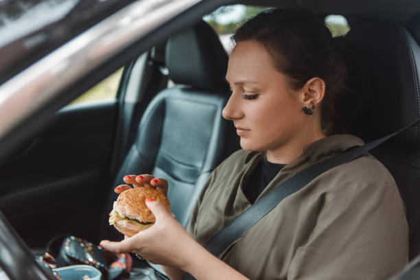 istock Distracted female driver eating at the wheel 1608312794