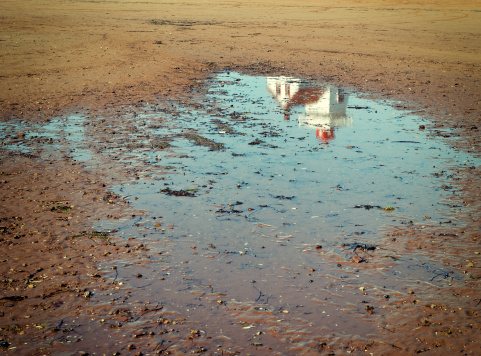 Lighthouse reflected in the puddle.