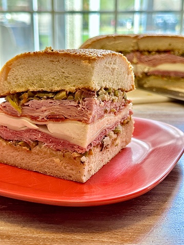 A giant muffuletta sandwich ready to be cut with a cleaver.