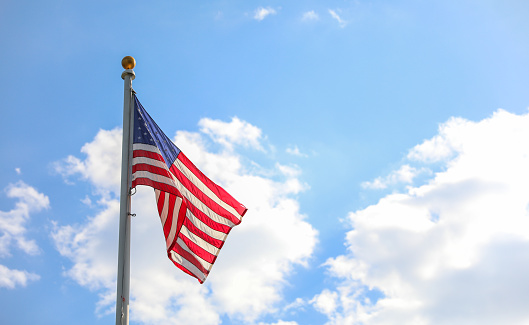 Close-up of American flag waving against blue sky.